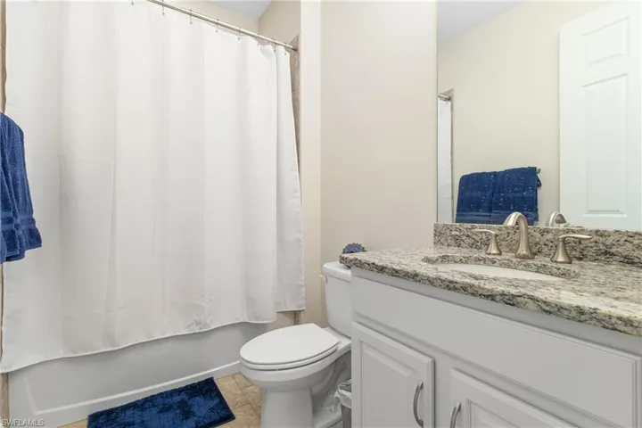 Full bathroom featuring vanity, shower / tub combo with curtain, toilet, and tile patterned floors