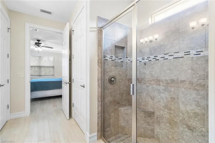 Bathroom featuring ceiling fan and an enclosed shower