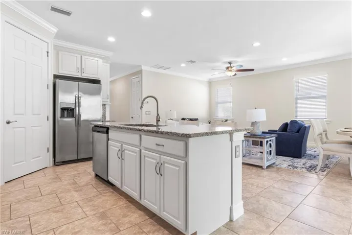 Kitchen featuring white cabinetry, crown molding, appliances with stainless steel finishes, and an island with sink