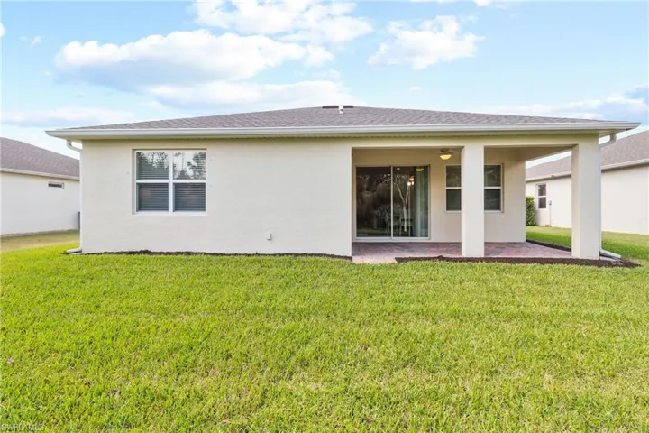 Rear view of house featuring a patio and a yard