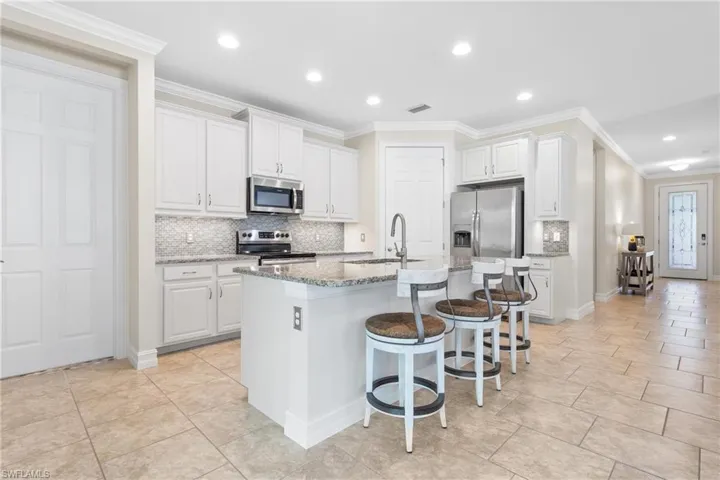Kitchen with stainless steel appliances, sink, a center island with sink, and white cabinets