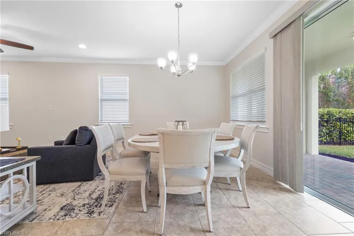 Dining room featuring crown molding, light tile patterned floors, and ceiling fan with notable chandelier