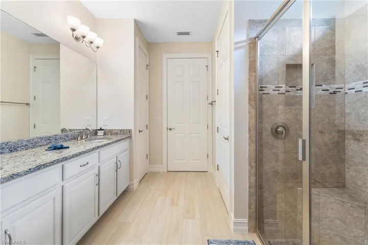 Bathroom with a shower with door, hardwood / wood-style flooring, and vanity