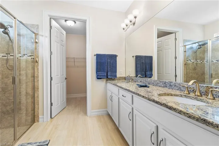 Bathroom with vanity, hardwood / wood-style floors, and a shower with shower door