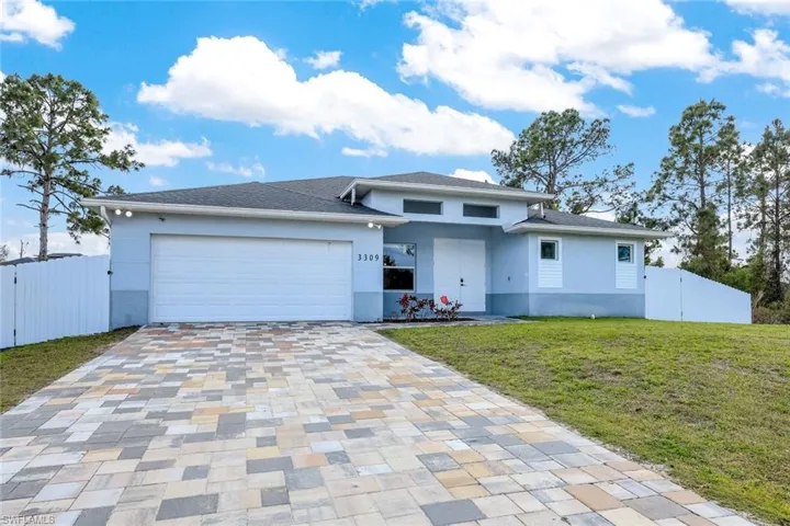 View of front of house with an attached garage, decorative driveway, stucco siding, and a gate