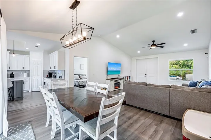 Dining area with a ceiling fan, dark wood-style flooring, lofted ceiling, and hanging lights