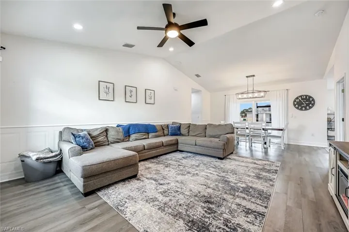 Living room with ceiling fan, light wood-style floors, lofted ceiling, and recessed lighting