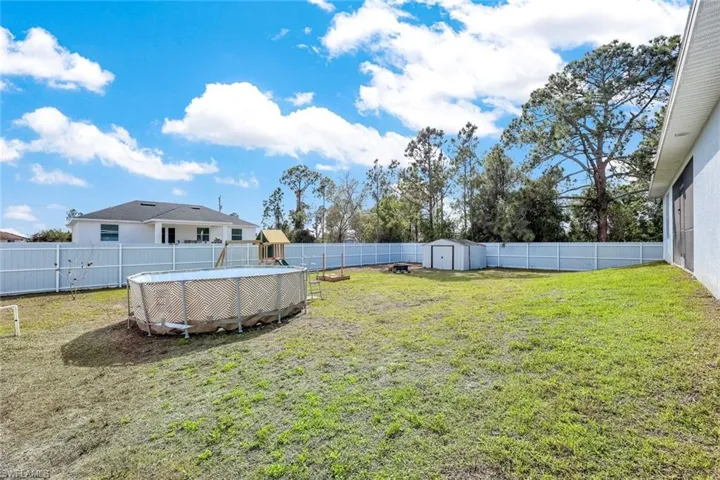 Fenced backyard featuring a shed