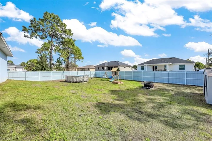 Fenced backyard featuring a residential view and a playground