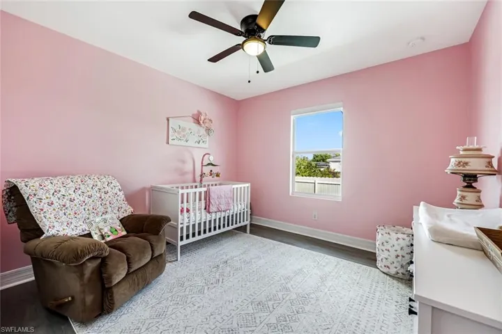Bedroom with a nursery area, ceiling fan, and light wood-type flooring