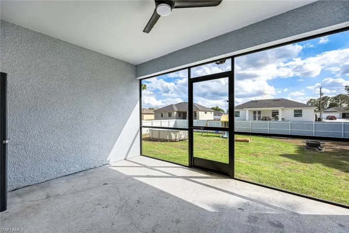 Unfurnished sunroom featuring a ceiling fan and a residential view