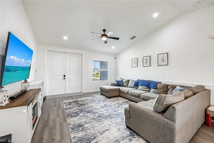 Living area featuring lofted ceiling, a ceiling fan, dark wood-style floors, and recessed lighting