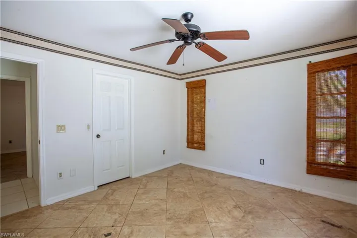 Empty room featuring a ceiling fan, light tile patterned floors, and baseboards
