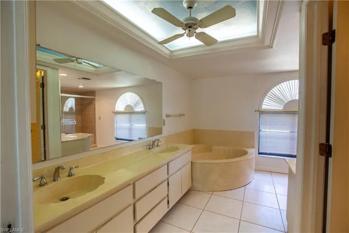 Bathroom with a skylight, plenty of natural light, tile patterned flooring, a stall shower, and crown molding