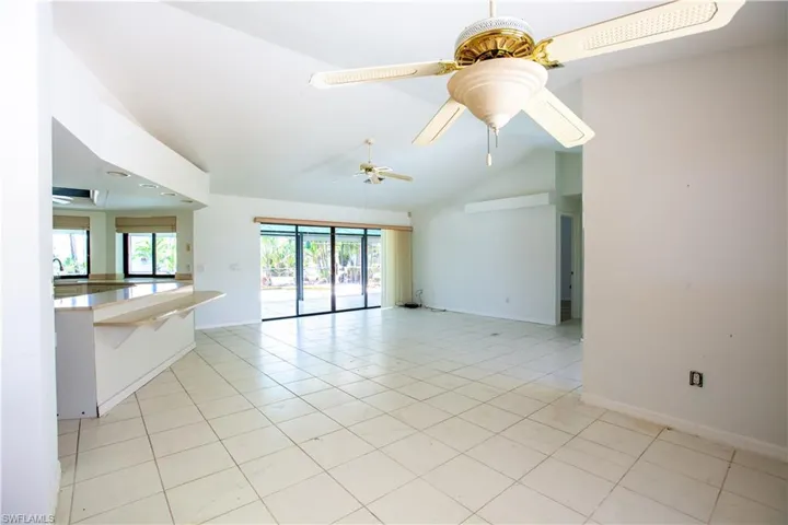 Unfurnished room with vaulted ceiling, light tile patterned floors, baseboards, and a ceiling fan