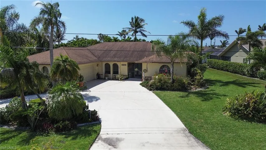 Mediterranean / spanish home with a garage, driveway, stucco siding, and a front lawn