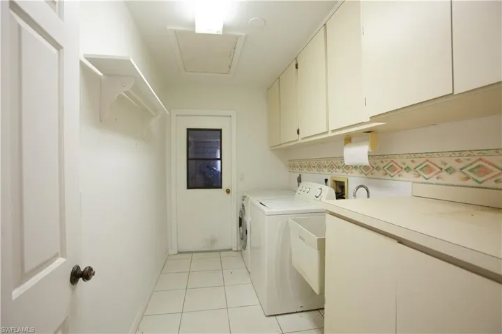 Washroom featuring cabinet space, washer and clothes dryer, light tile patterned floors, and baseboards