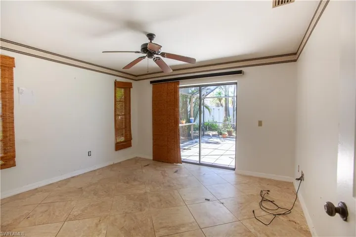 Spare room featuring a ceiling fan, baseboards, crown molding, and light tile patterned floors