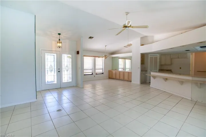 Unfurnished living room with ceiling fan, lofted ceiling, french doors, baseboards, and light tile patterned floors