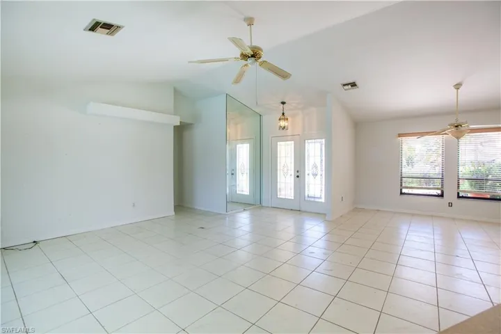Unfurnished room featuring a ceiling fan, lofted ceiling, light tile patterned floors, and baseboards