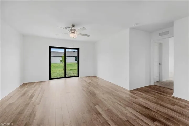 Spacious room featuring wood-finish flooring and white walls