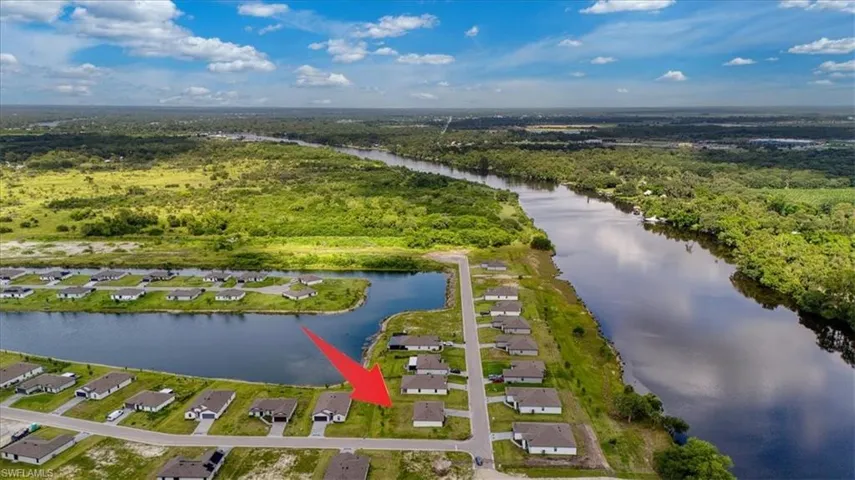 Aerial perspective showcasing a residential community alongside the Caloosahatchee River and a community lake