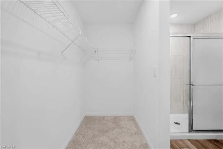 Walk-in closet with wire shelving and carpet flooring in the primary bathroom