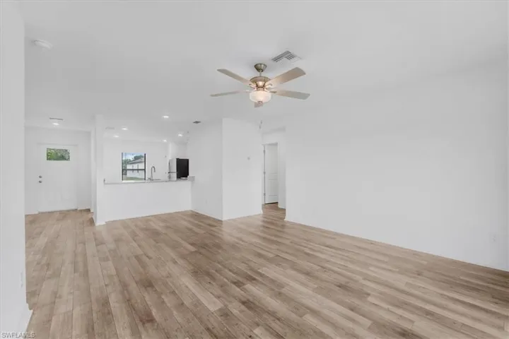Open-concept living area featuring wood-finish flooring, a ceiling fan with light fixture, recessed lighting, and a breakfast bar