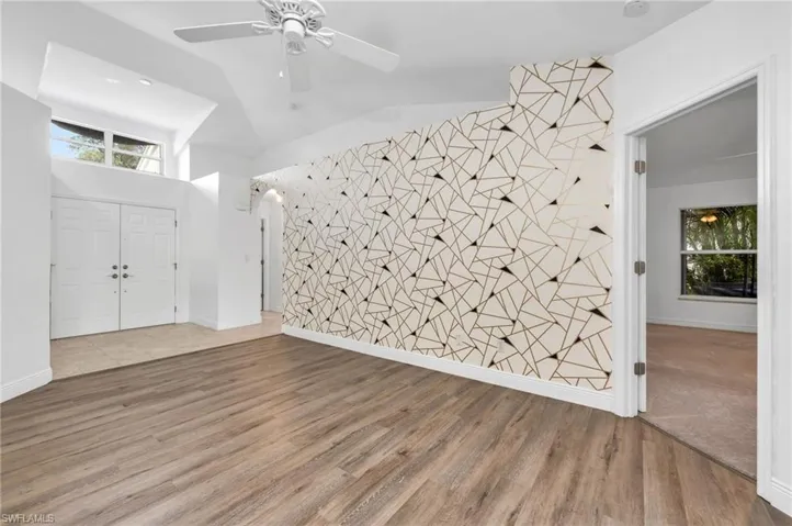 Foyer with ceiling fan, vaulted ceiling, and wood-type flooring