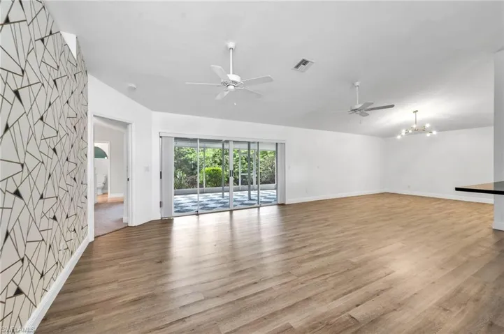 Spare room with lofted ceiling, ceiling fan with notable chandelier, and light wood-type flooring