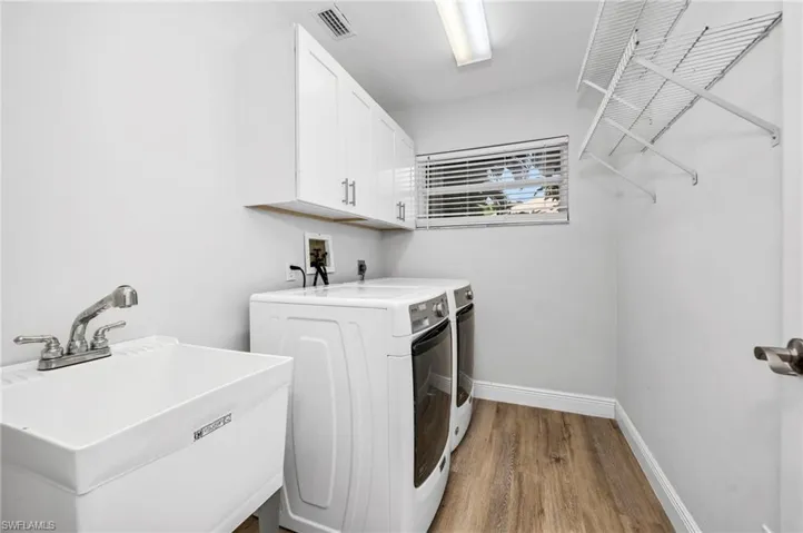 Laundry area with cabinets, light wood-type flooring, sink, and washing machine and dryer