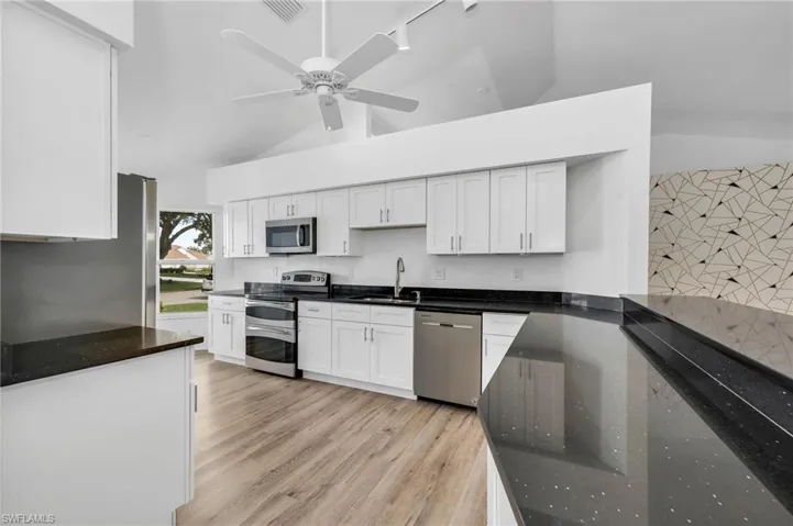 Kitchen featuring ceiling fan, white cabinets
