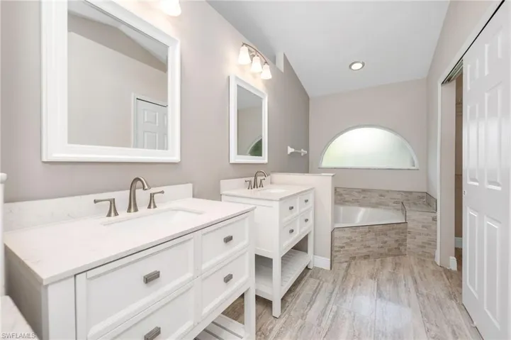 master bathroom featuring vanity, wood-type flooring, and tiled bath