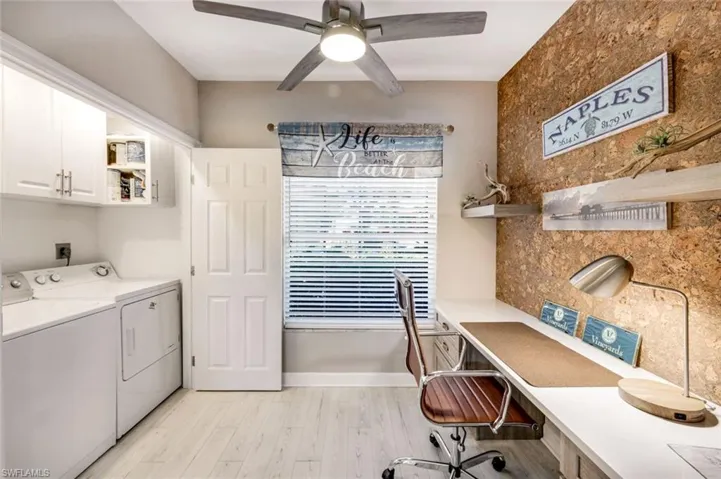 Laundry area featuring a desk, light wood finished floors, a ceiling fan, cabinet space, and separate washer and dryer