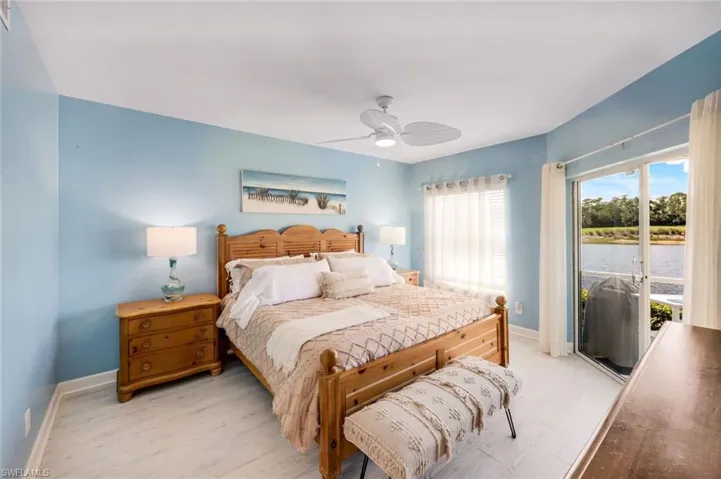 Primary Bedroom with access to outside, wood finished floors, a water view, and a ceiling fan