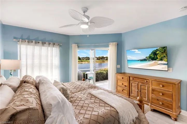 Primary Bedroom with access to exterior, a ceiling fan, and wood finished floors