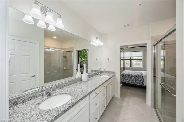 Bathroom with ensuite bath, a shower stall, double vanity, and plenty of natural light