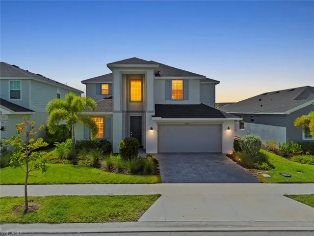Two-story exterior with a covered entry, attached garage, and a paver driveway