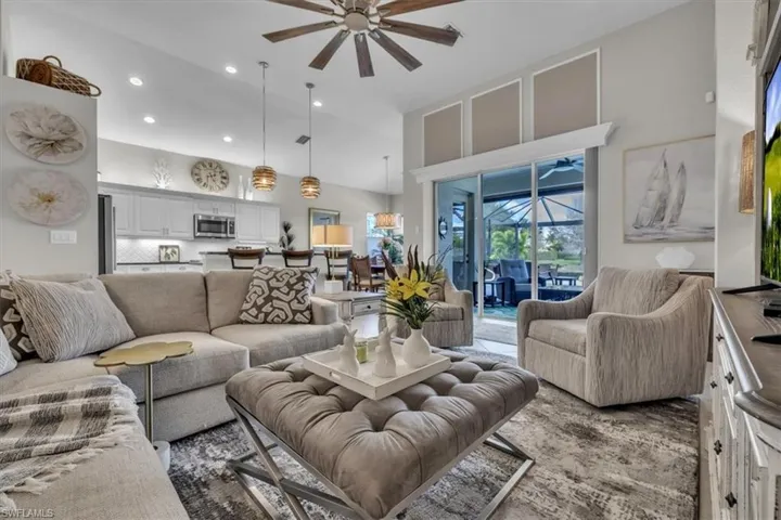 Living room with a ceiling fan, a sunroom, a high ceiling, and recessed lighting
