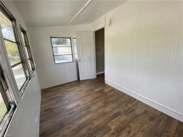 Empty room with dark wood-style floors and wood walls