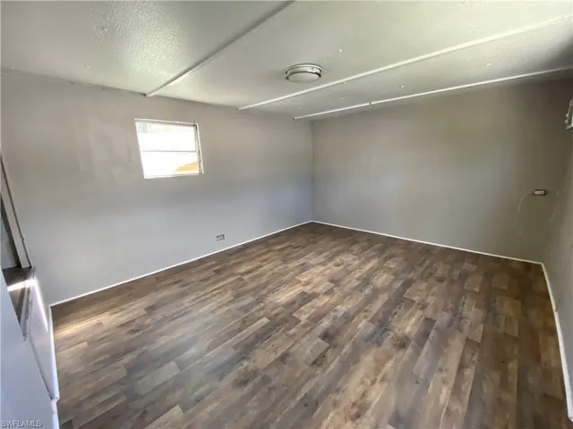 Spare room with a textured ceiling and dark wood-type flooring
