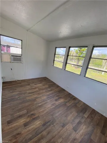 Empty room with a textured ceiling and dark wood finished floors