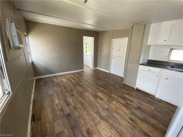 Kitchen featuring white cabinetry, dark countertops, dark wood-type flooring, and a wall unit AC
