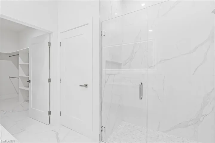 Bathroom with light marble finish flooring and a marble finish shower