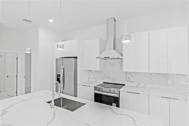 Kitchen with modern cabinets, decorative light fixtures, extractor fan, white cabinetry, and recessed lighting