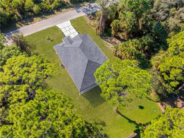 Aerial view of property and surrounding area featuring a tree filled landscape