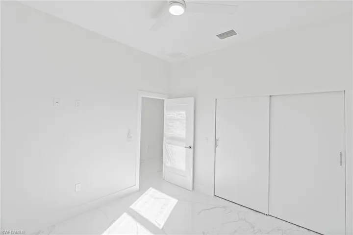 Unfurnished bedroom featuring light marble finish flooring, ceiling fan, and a closet