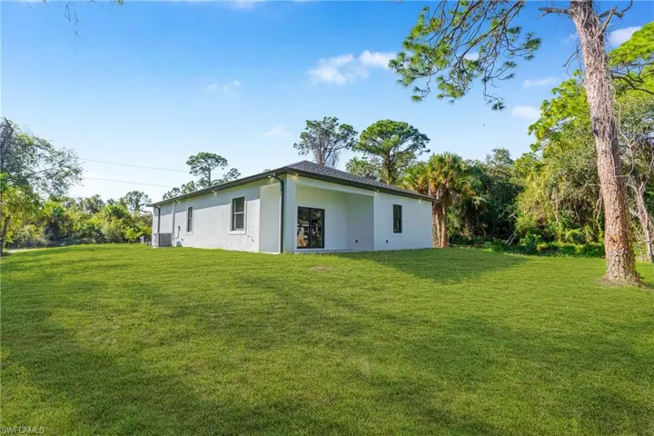Rear view of property with a yard and stucco siding