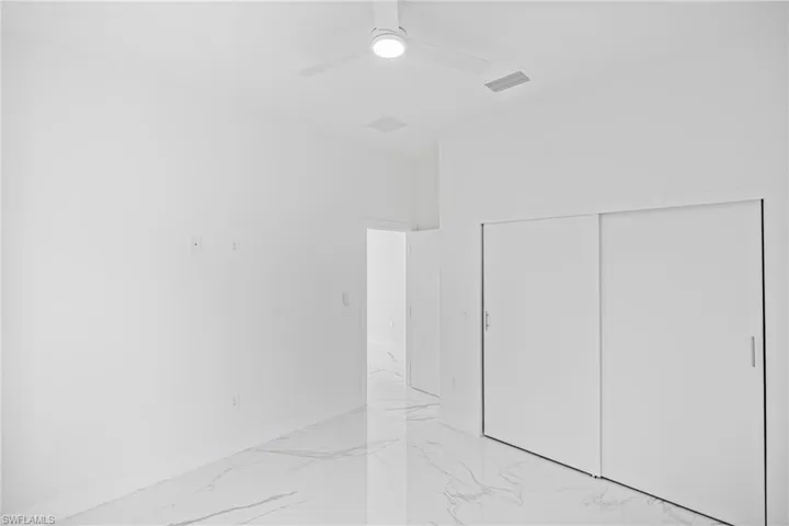 Spare room with light marble finish floors and a ceiling fan