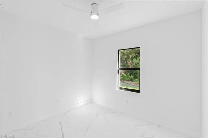 Empty room with marble look tiles and ceiling fan